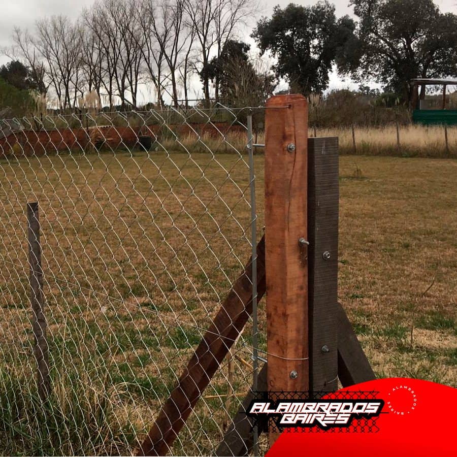 Esquinero de madera con puntal sosteniendo el tejido de un alambrado de campo.