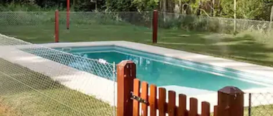 Pileta rodeada por un cerco de tejido con puerta de madera.